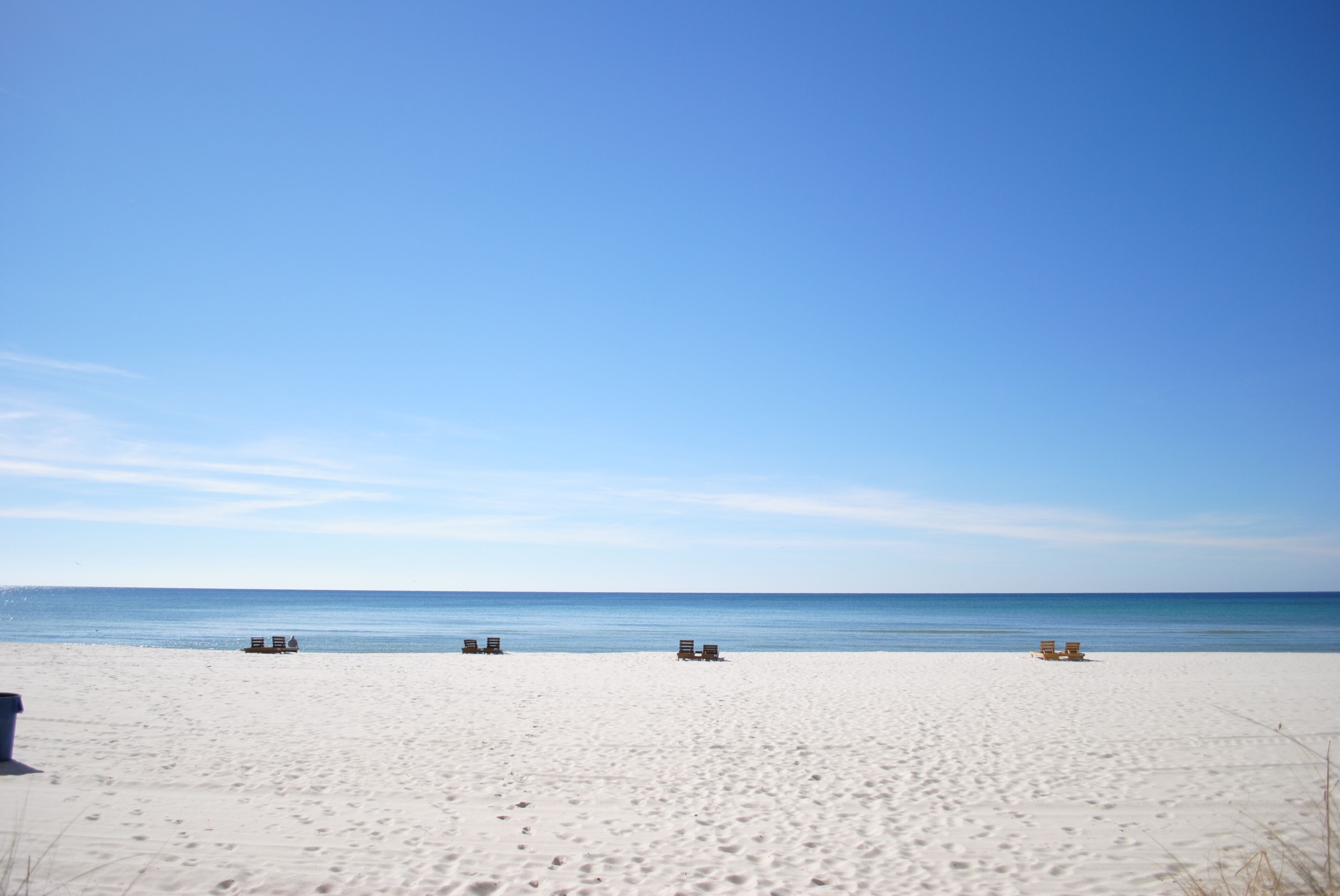 A beach with several empty beach chairs and a clear blue sky.