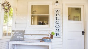 A white exterior with a bench, a welcome sign, and a door. - Beautiful Chico Farmhouse With Room for All…10 beds!! (Chico)