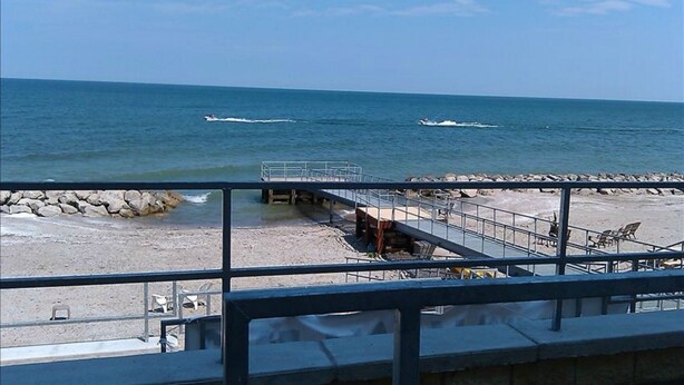 A beach with a pier, seating area, and a view of the ocean. - LAKEFRONT CONDO#111 3BR/2BA-private beach, indoor pool  Rent 3 get 4th free-ask (Geneva on the Lake)