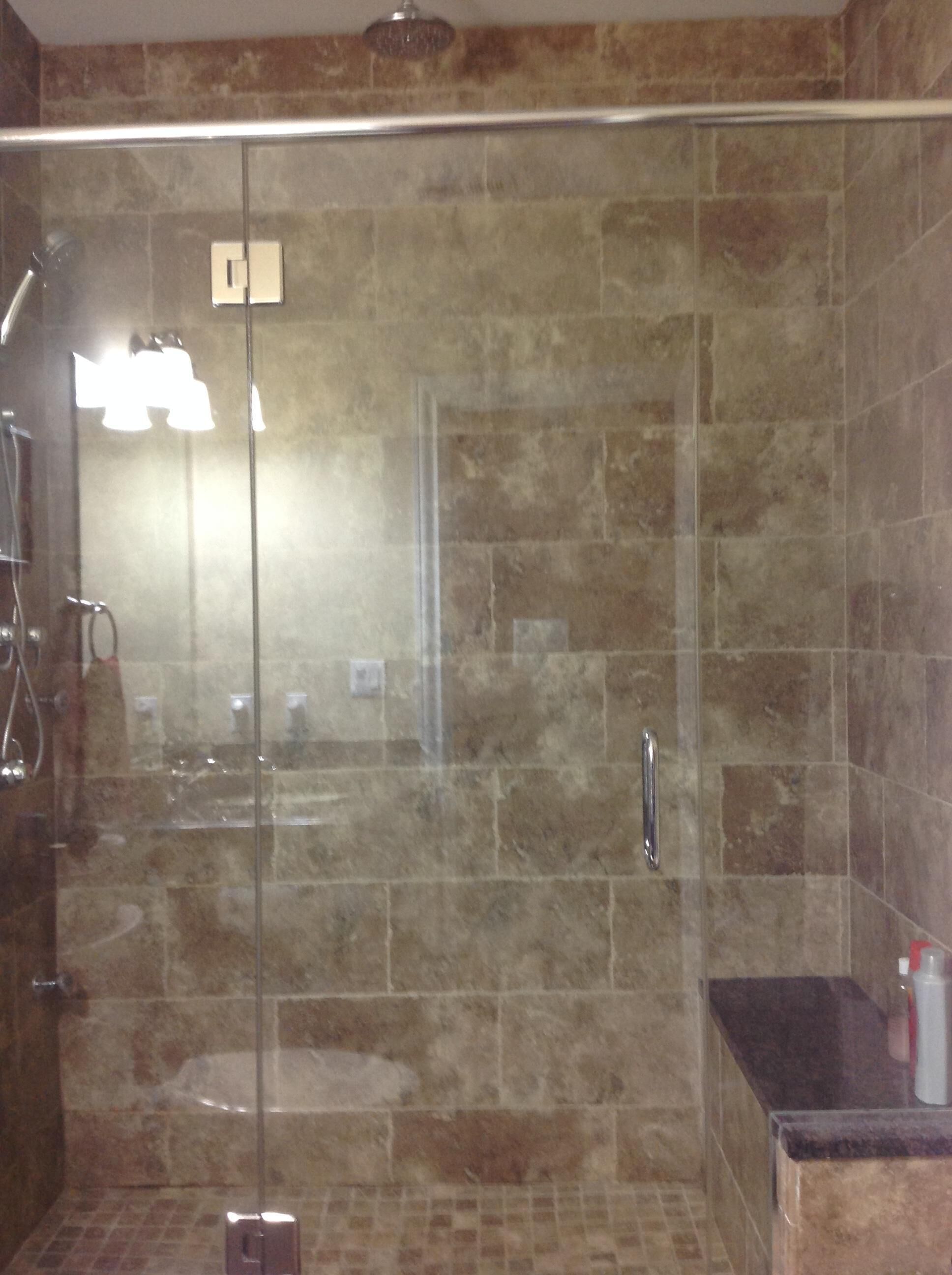 A glass-enclosed shower area with a tiled wall, a visible handrail, and a control panel.