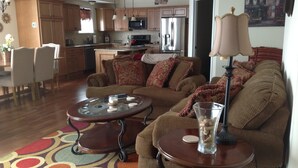 A living room with a sofa, two coffee tables, and a lamp. There is a kitchen in the background with cabinets and appliances. - LAKEFRONT CONDO#111 3BR/2BA-private beach, indoor pool  Rent 3 get 4th free-ask (Geneva on the Lake)