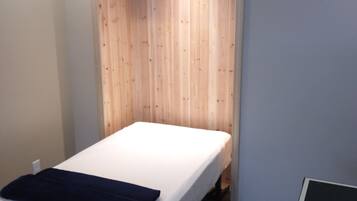 Cozy retreat with a single bed, dark wood flooring, and a compact table.