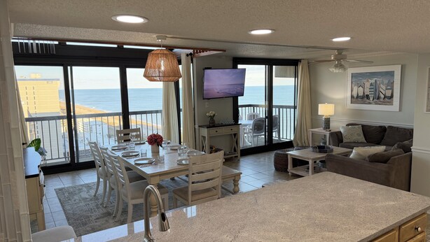 A spacious living area with a kitchen, dining area, and a balcony with a view of the ocean. - Oceanfront Penthouse, great views, Best Amenities, Spacious Sleeps 14, 3 Pools (Ocean City)