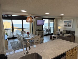 Un'ampia zona giorno con cucina, sala da pranzo e un balcone vista oceano.