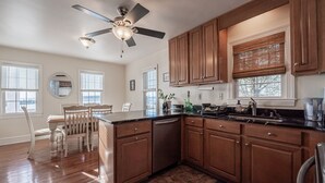 A kitchen with wooden cabinets, a black countertop, and a ceiling fan.