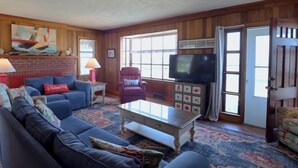 A cozy living room with a blue sofa, a red armchair, a coffee table, and a television.