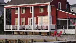 A two-story red house with a white porch and a small deck.