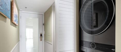 A laundry room with a large black washer and dryer, a white door, and a painting on the wall.