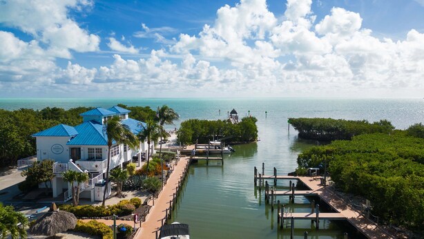 A coastal hotel with a dock, clear water, and a view of the sea.