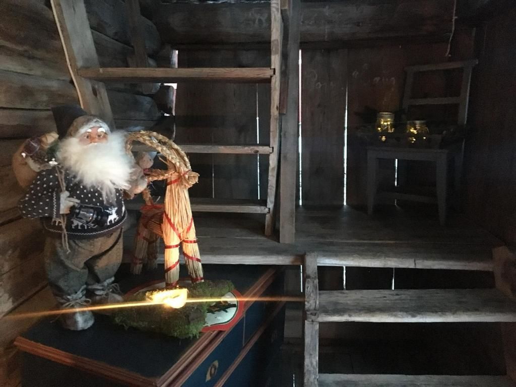 Un intérieur rustique avec une étagère en bois, une petite table ornée de bougies et une figurine décorative.