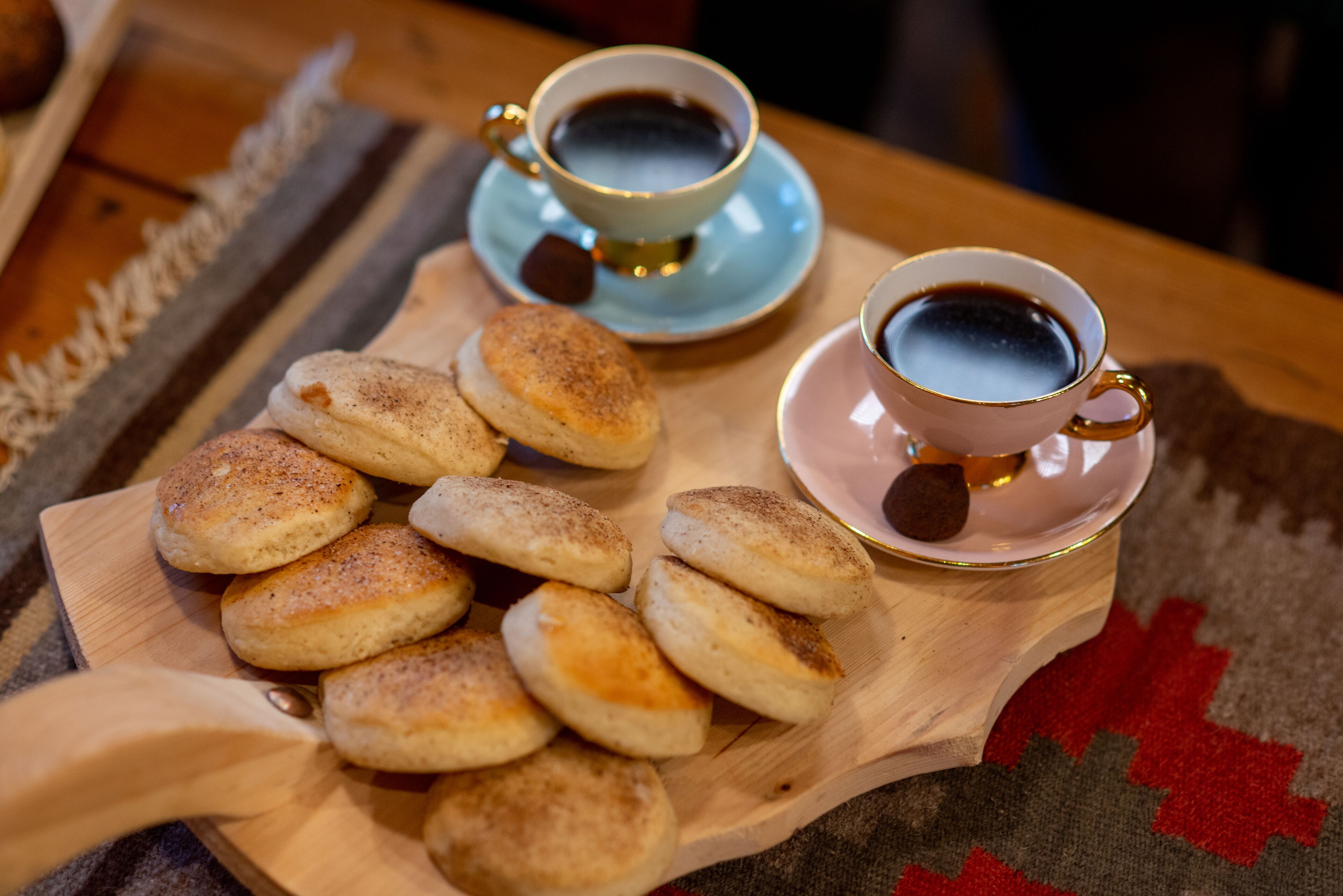Un plateau en bois contenant des pâtisseries et deux tasses de café, posé sur une table.