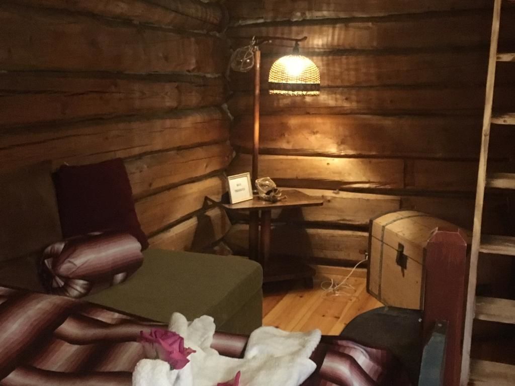 Una cabana acollidora amb interior de fusta, una taula petita amb una làmpada i un llit amb un mantell verd.