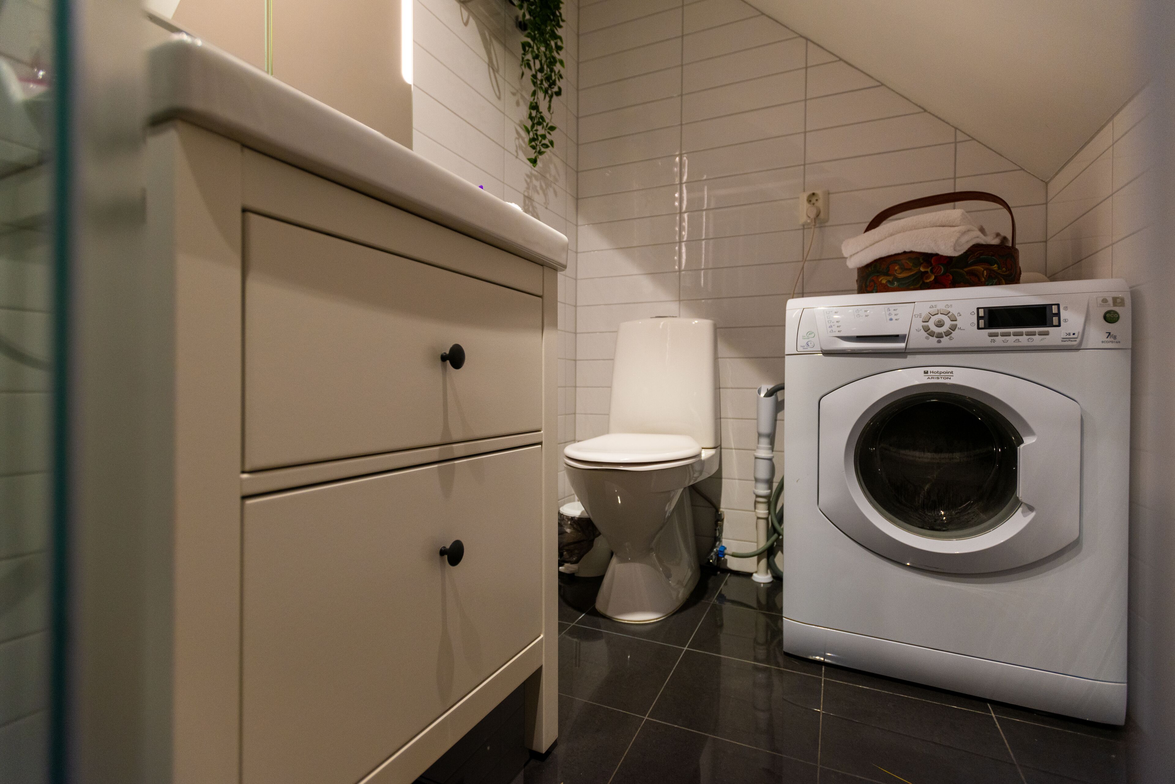 A compact bathroom with a washing machine, a toilet, and a cabinet.