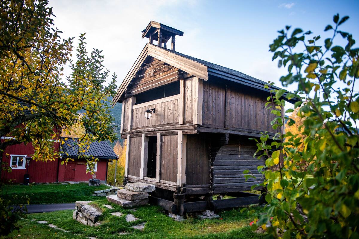 A rustic wooden cabin with a steeply pitched roof, a chimney, and a small porch.