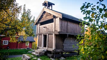 A rustic wooden cabin with a steeply pitched roof, a chimney, and a small porch.