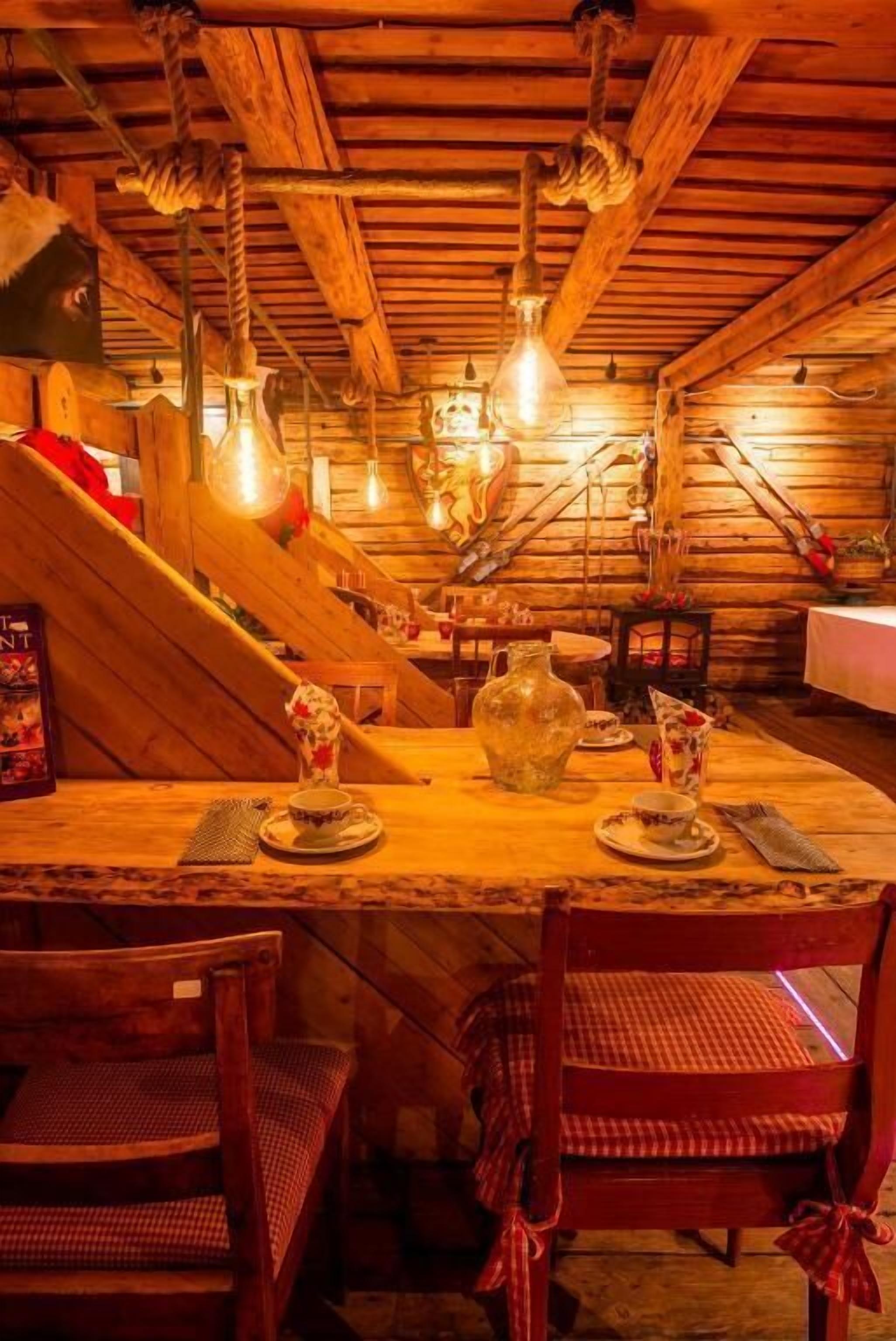 Un comedor rústico de madera con una mesa para dos, rodeada de sillas de madera.