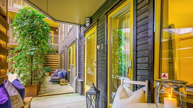 Una terraza de madera con una planta en maceta, un farol y una mesa con una vela.