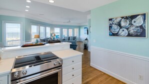 A modern kitchen with a stainless steel range, white cabinetry, and a large window providing natural light. - Oceanview with Sunrise Views, Direct Beach Access & Hot Tub (Tybee Island)