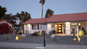 A two-story building with a red-tiled roof, a front entrance with a door, and a mailbox.