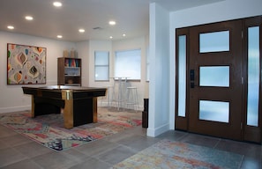 Relax in this stylish room with a pool table, bookshelf, and abstract art, perfect for unwinding and socializing.
