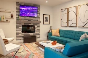 Relax in this stylish living room with a sofa, flat-screen TV, and a framed picture above.