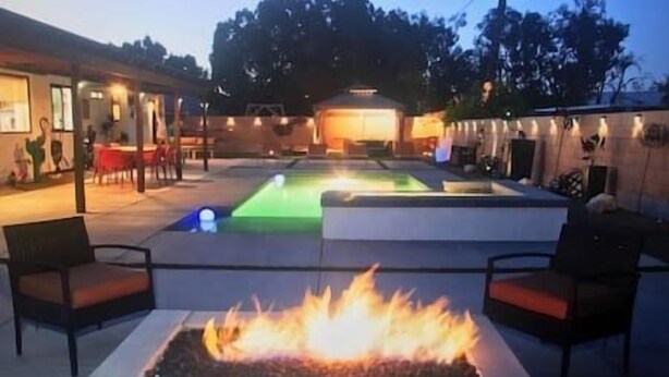 An outdoor patio area with a fire pit, seating, and a pool.