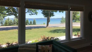 A room with a large window overlooking a grassy area and a body of water. - The Bay View Brick --Stunning View of Bay 
 (Traverse City)