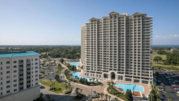 A high-rise hotel with multiple balconies, a swimming pool, and a view of the surrounding landscape. - Ariel Dunes #2107 2BR/2BA - Gorgeous Gulf Views (Miramar Beach)