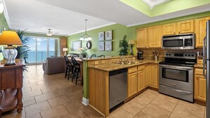 A modern kitchen with wooden cabinets, stainless steel appliances, and a large island. - Ariel Dunes #2107 2BR/2BA - Gorgeous Gulf Views (Miramar Beach)