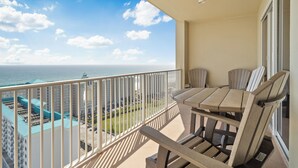 A balcony with a table and chairs, overlooking a cityscape and the ocean. - Ariel Dunes #2107 2BR/2BA - Gorgeous Gulf Views (Miramar Beach)