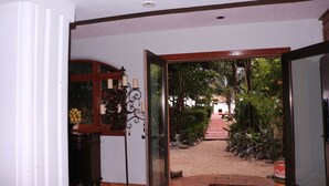 A doorway leading to a garden with a pathway, a wooden cabinet with decorative items, and a tiled floor. - Paradise Found!  Beautiful Private Villa On The Sea in the Village of Placencia! (Placencia Village)