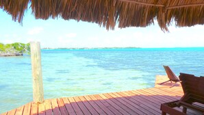A wooden deck with a thatched roof, overlooking a clear blue sea. - Paradise Found!  Beautiful Private Villa On The Sea in the Village of Placencia! (Placencia Village)
