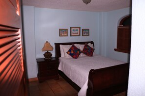 Un dormitorio con cama, mesita de noche, lámpara y tres cuadros en la pared.