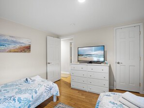 A bedroom with a bed, a dresser, a television, and a painting on the wall.