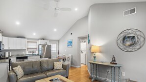 A modern living room with a grey leather sofa, wooden coffee table, and a dining area with a small table and chairs. - Brand New Luxurious Town Home, 600 Feet To Englewood Beach (Yarmouth)
