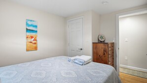 A bedroom with a bed, a door, a dresser, and a painting on the wall. - Brand New Luxurious Town Home, 600 Feet To Englewood Beach (Yarmouth)