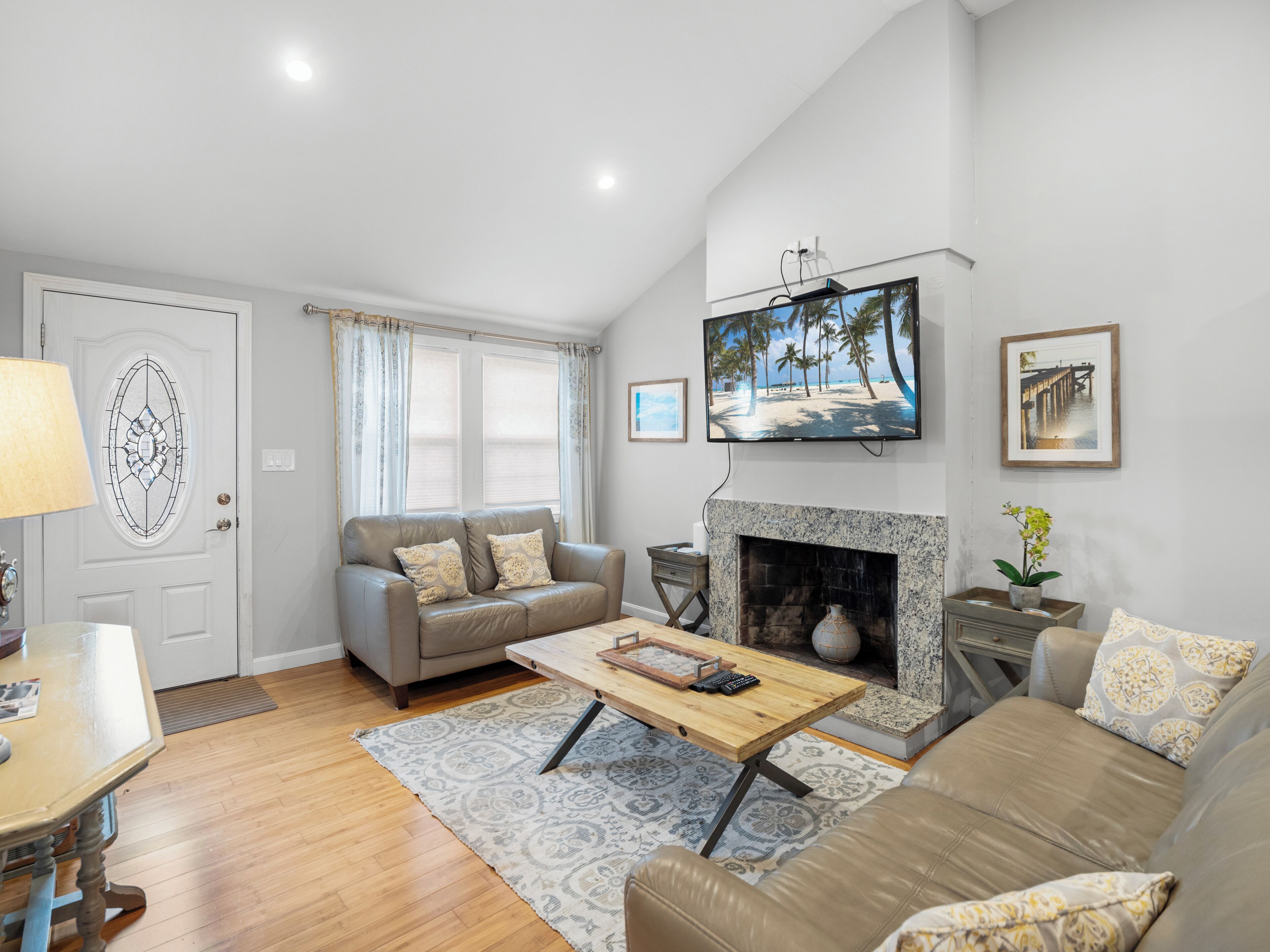 A living room with a fireplace, a television mounted above it, and a sofa.