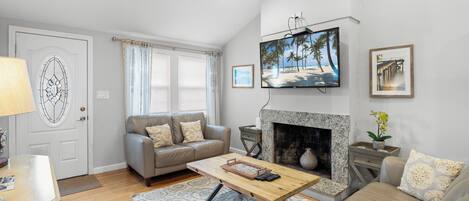 A living room with a fireplace, a television mounted above it, and a sofa.