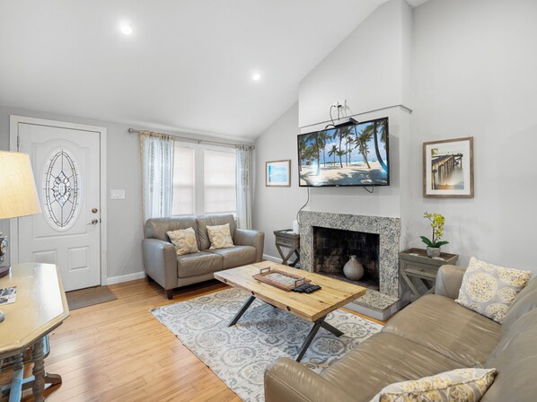 A living room with a fireplace, a television mounted above it, and a sofa.