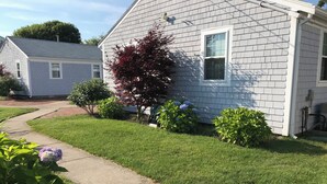 A residential property with a well-maintained lawn, a pathway leading to the house, and a variety of shrubs and flowers. - Brand New Luxurious Town Home, 600 Feet To Englewood Beach (Yarmouth)