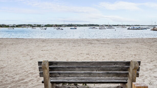 A beach with a wooden bench in the foreground and several boats on the water. - Brand New Luxurious Town Home, 600 Feet To Englewood Beach (Yarmouth)