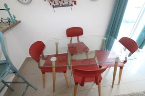 Un coin repas avec une table à plateau en verre et quatre chaises rouges.