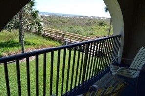 Un balcon donnant sur un espace verdoyant et une promenade en bois.