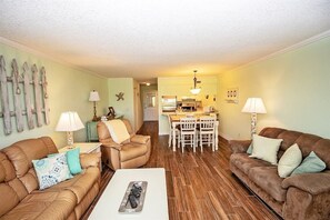 A living room with two sofas, a coffee table, and a dining area with a table and chairs. - Ponce Landing 7 (Saint Augustine)