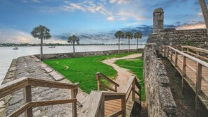 A coastal walkway with a stone wall, wooden railings, and a grassy area. - Ponce Landing 7 - Oceanfront Townhome - Heated Pool (Saint Augustine)