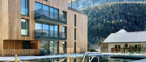 A modern building with a wooden facade, large windows, and a balcony.