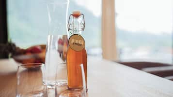 Una botella de vidrio con la etiqueta 'gingi syrup' y dos vasos de vidrio sobre una superficie de madera.