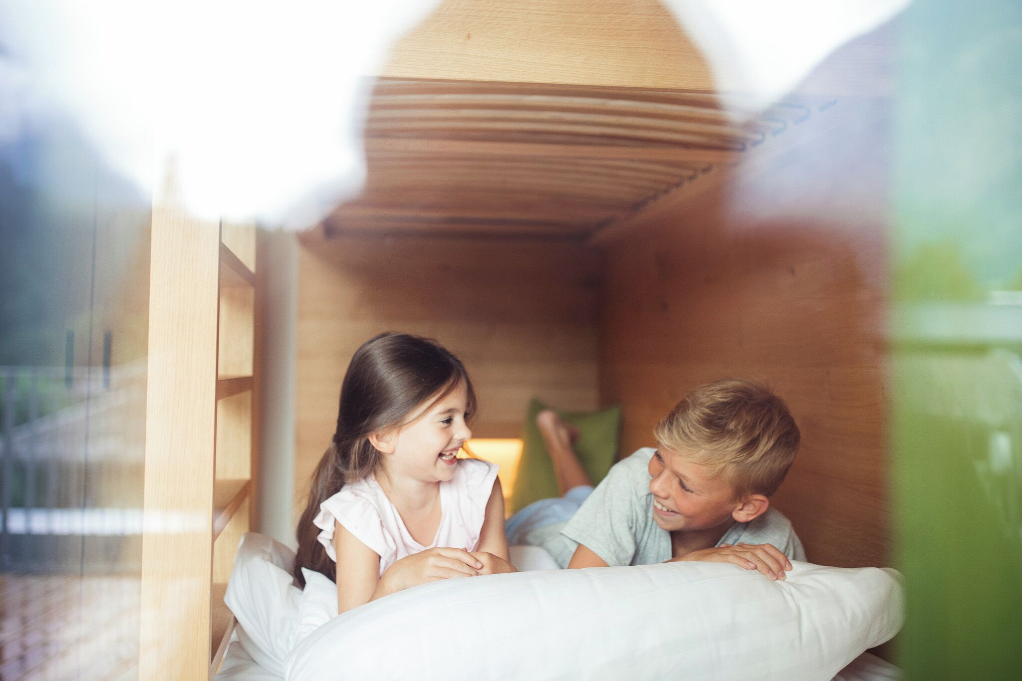 Una habitación con una cama litera de madera y una ventana.