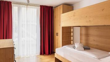 Ein Zimmer mit einem Etagenbett, einem Holzschrank und einem Schreibtisch.