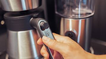 Una mà manipula una màquina de cafè amb un pantalla digital.